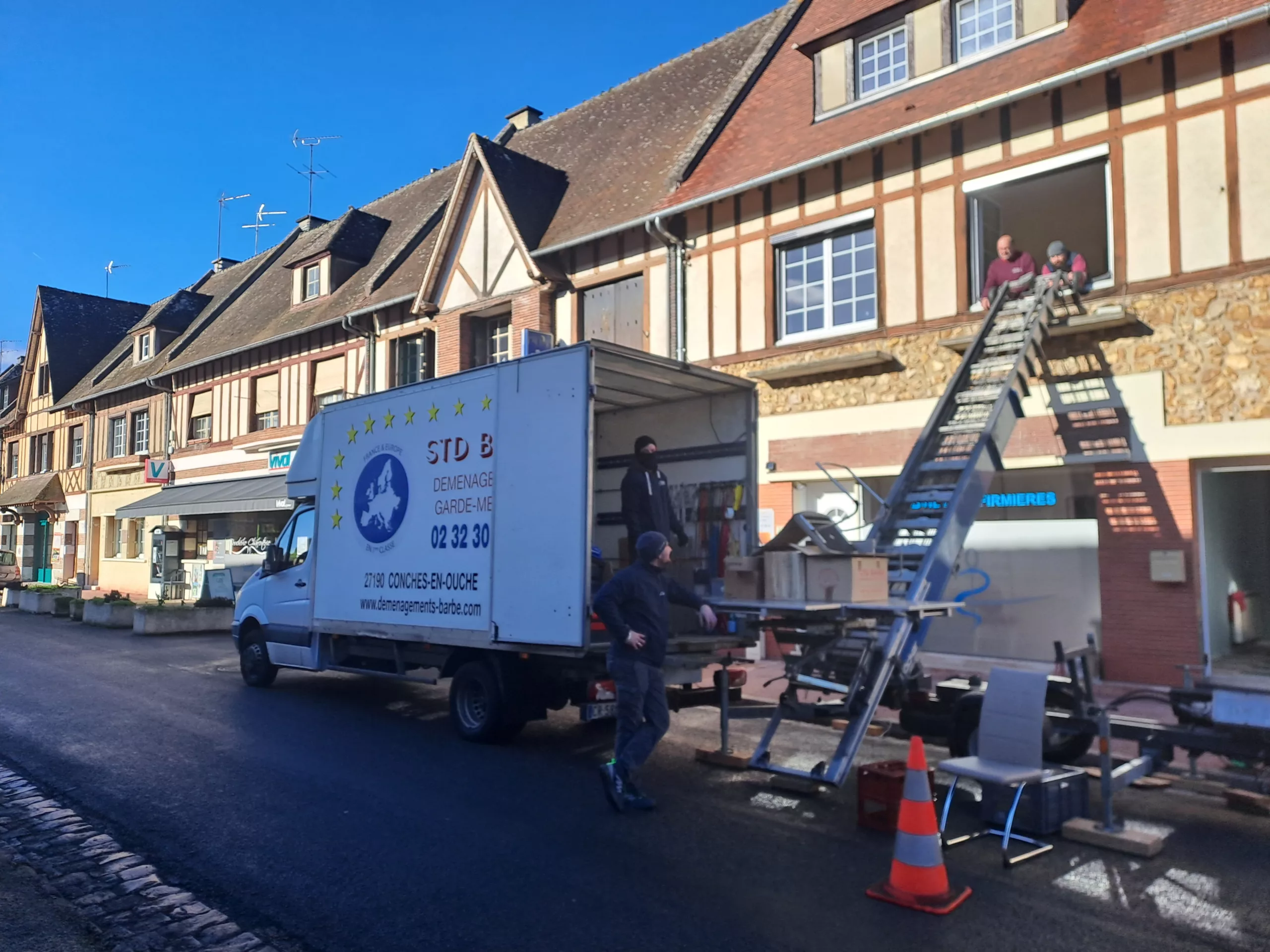 Un homme est en train de charger un camion sur une rue, organisant soigneusement les marchandises.